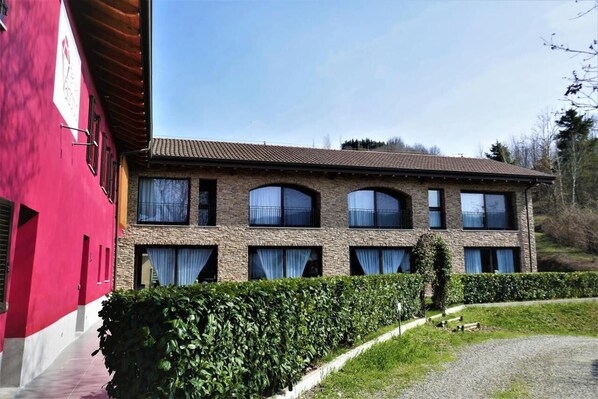 A two-story building with a brick facade, large windows, and a red building adjacent to it. - TENUTA VALDORSO AGRI RESORT (Montechiaro d'Acqui)