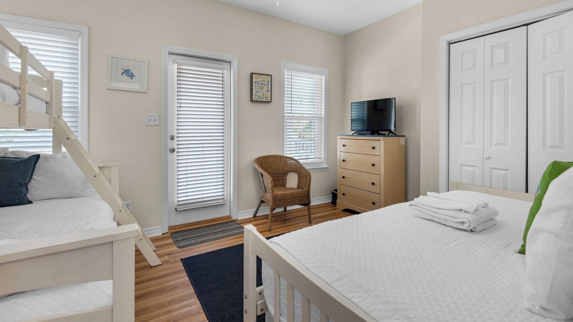 Une chambre comprenant un lit superposé, un lit simple, une commode, une chaise, un téléviseur et un placard.