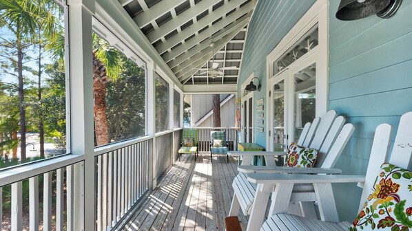 A covered porch with a view of trees and a building in the background.