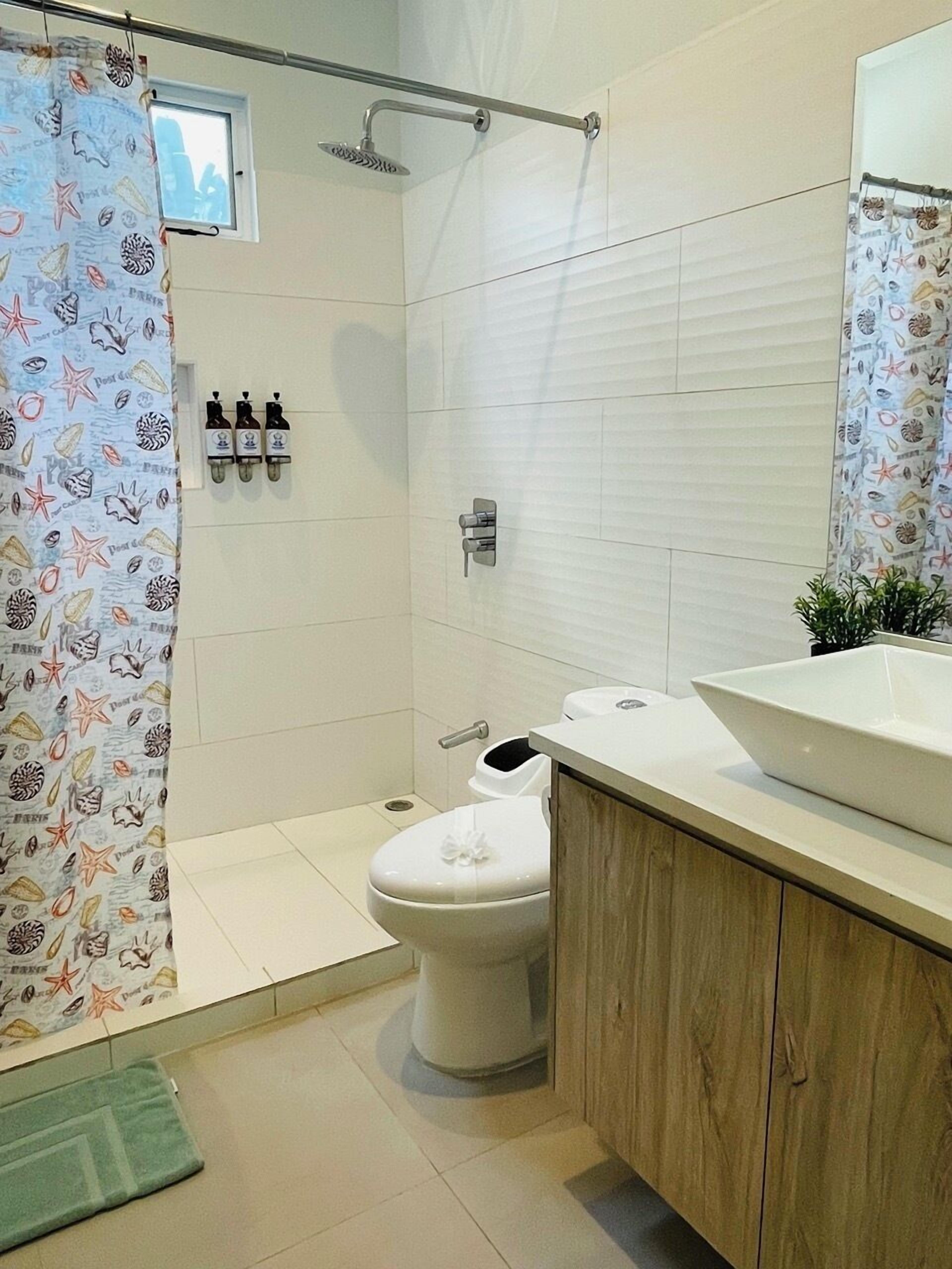 A bathroom with a shower, toilet, and sink.