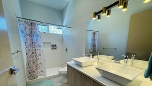 A modern bathroom with two sinks, a shower, and a toilet. - Casa Lapa Roja (Jacó)