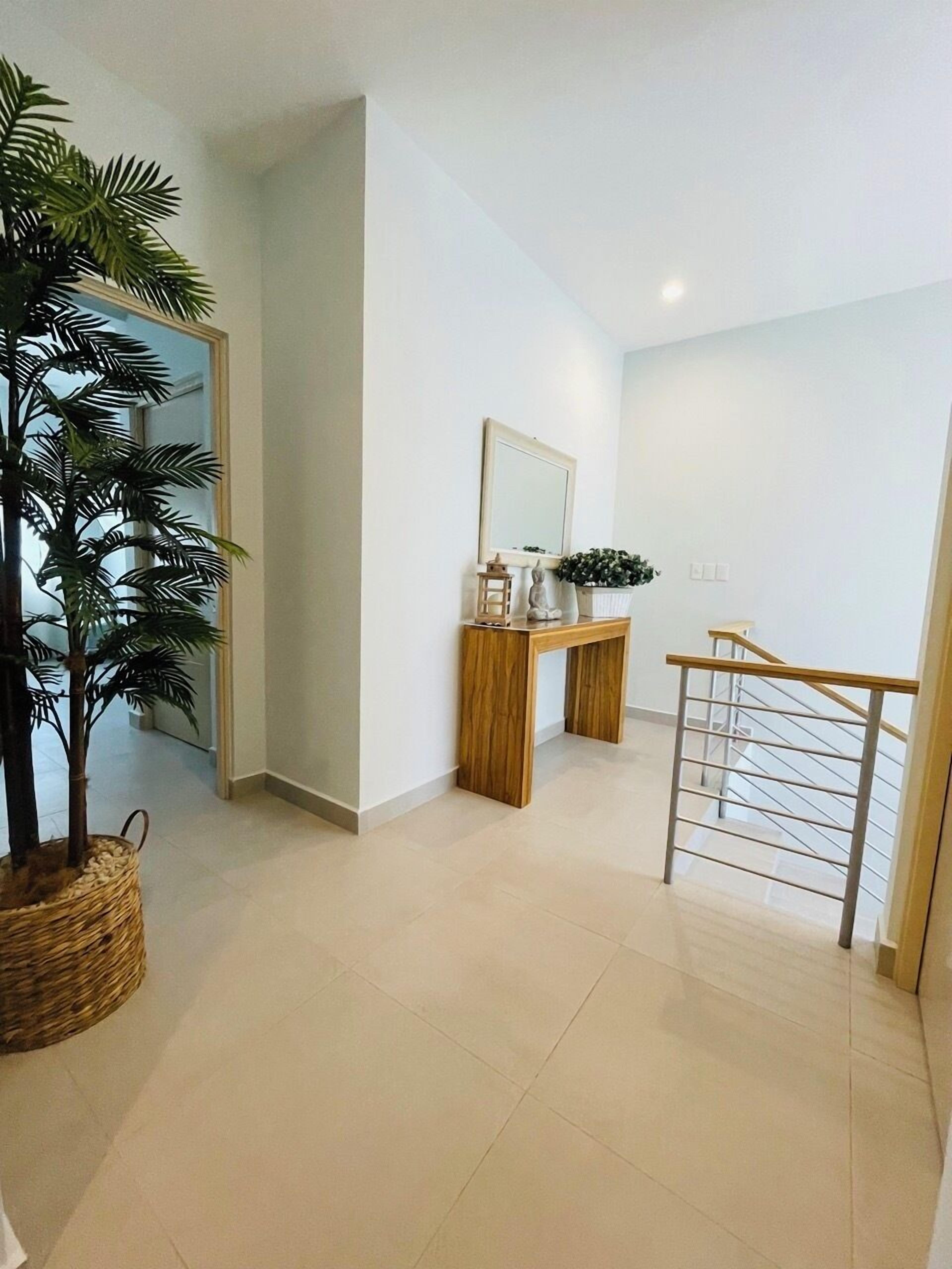 Een modern interieur met een trap, een houten consoletafel, een potplant en een spiegel.
