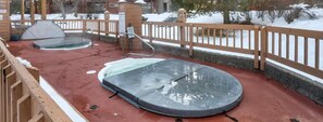 A hot tub area with a wooden deck and a metal railing.