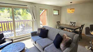 A cozy living room with a gray sofa, two round coffee tables, and a dining table with chairs. - 3 Bedroom Centrally Located Ski In/Ski Out Condo in Panorama (Panorama)