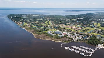 An aerial view of a coastal area with a marina, residential buildings, and golf courses.