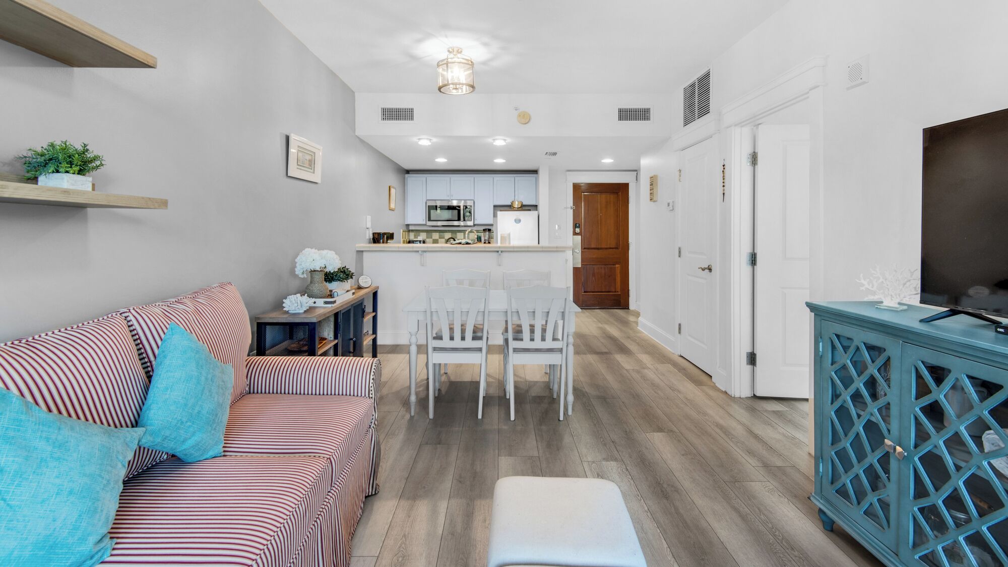 Una sala de estar moderna con un sofá a rayas, una mesa de comedor con sillas y una cocina al fondo.