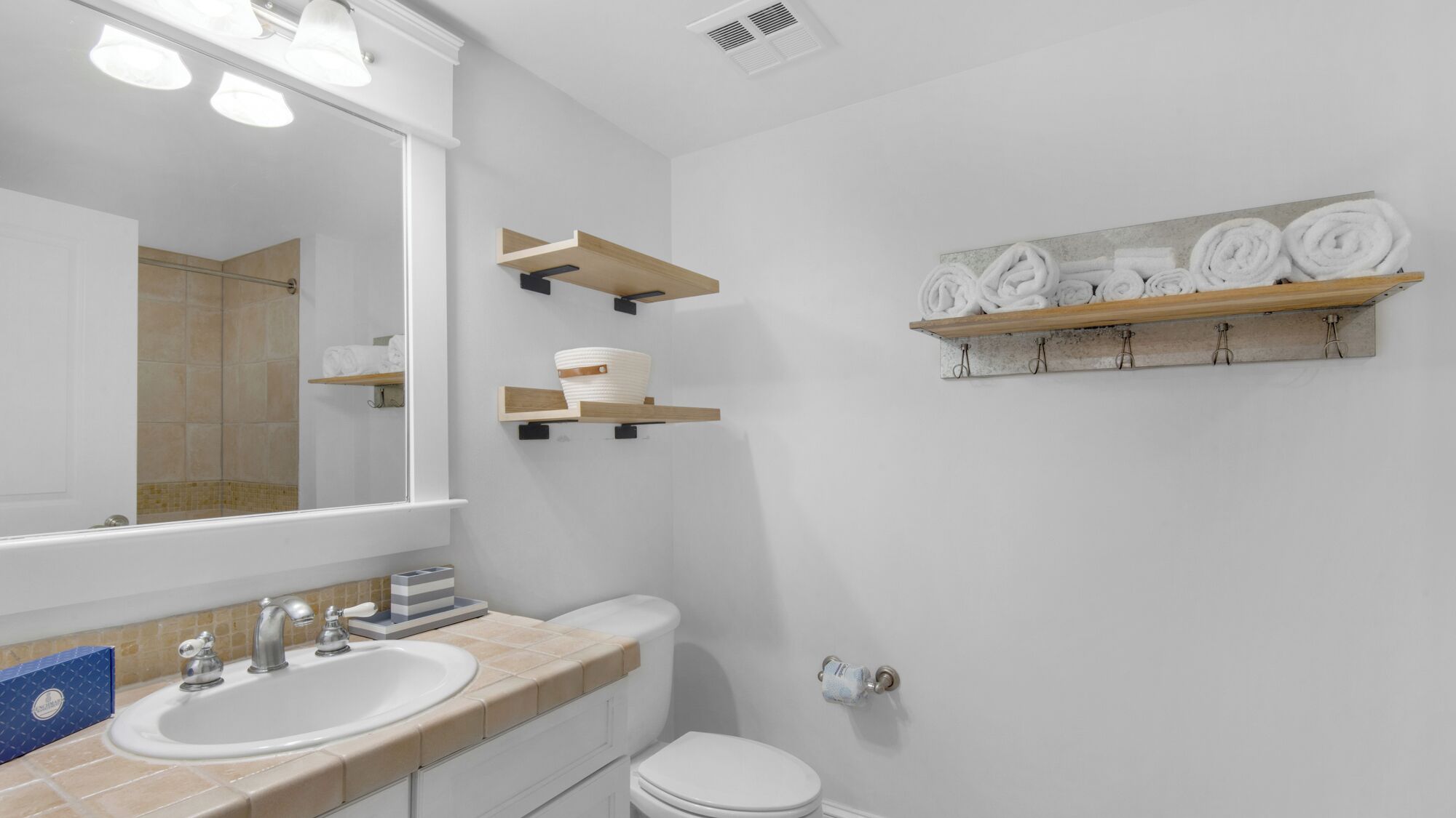 A bathroom with a large mirror, a sink, a toilet, and towel racks.