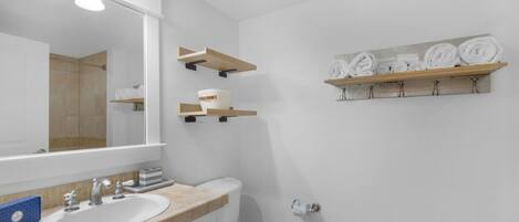 A bathroom with a large mirror, a sink, a toilet, and towel racks.