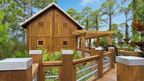 A wooden cabin with a porch, surrounded by a wooden fence and a metal gate. - Steps From Baytowne Wharf With Pool & Private Beach Access (Miramar Beach)