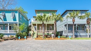A row of historic houses with front porches, palm trees, and a clear blue sky.