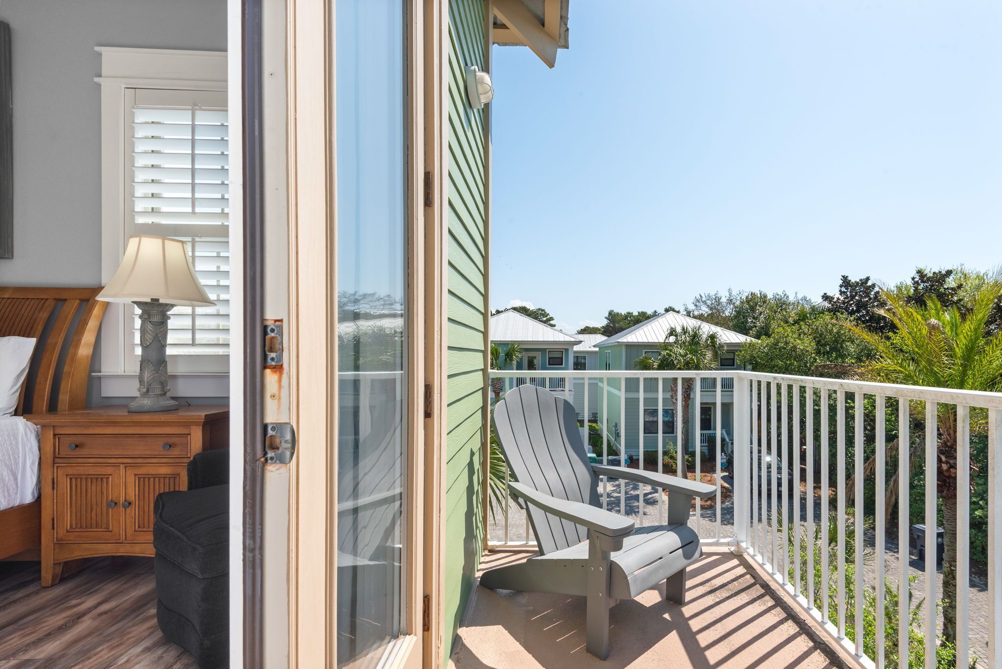 A balcony with a chair, a lamp, and a view of the ocean and other buildings.