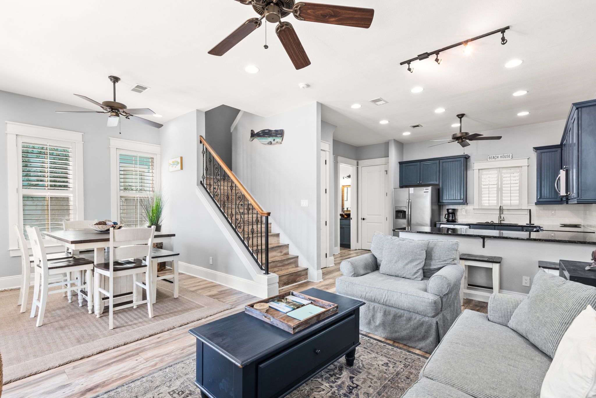 A spacious living area with a dining table, sofas, a coffee table, and ceiling fans.