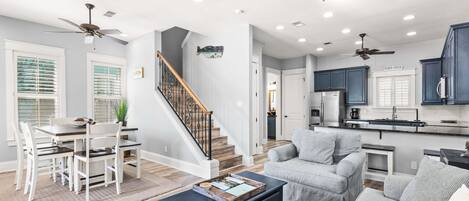 A spacious living area with a dining table, sofas, a coffee table, and ceiling fans.