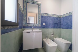 Bathroom features a white sink, mirror, cabinets, bathtub, and toilet.