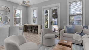 A modern living room with a grey sofa, armchairs, a coffee table, and a dining area with a wooden table and bar stools. - Steps From the Seagrove Beach - Gulf Views - Sleeps 10 - Community Pool (Santa Rosa Beach)