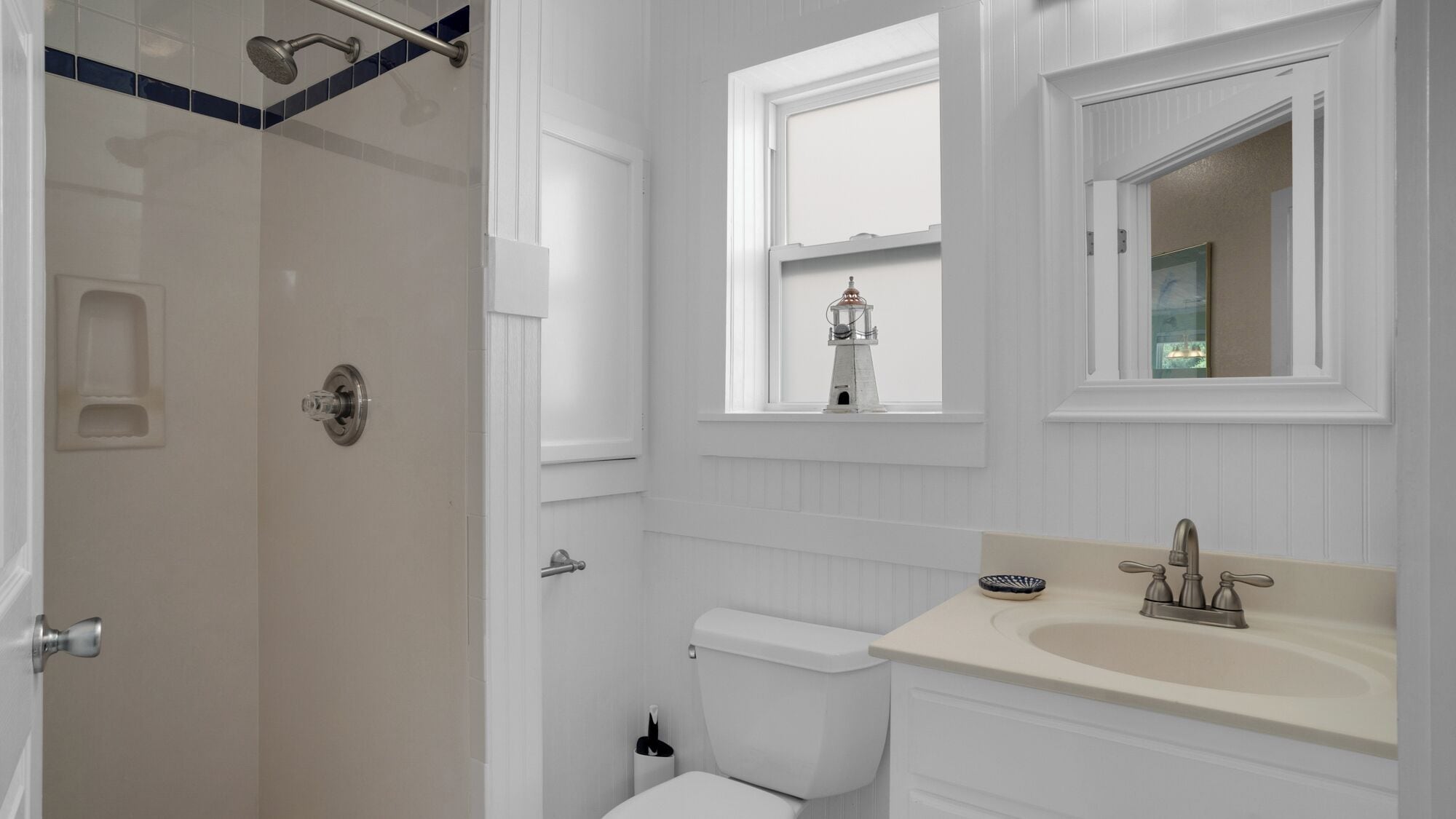 Een badkamer met douche, toilet, wastafel en raam met uitzicht.