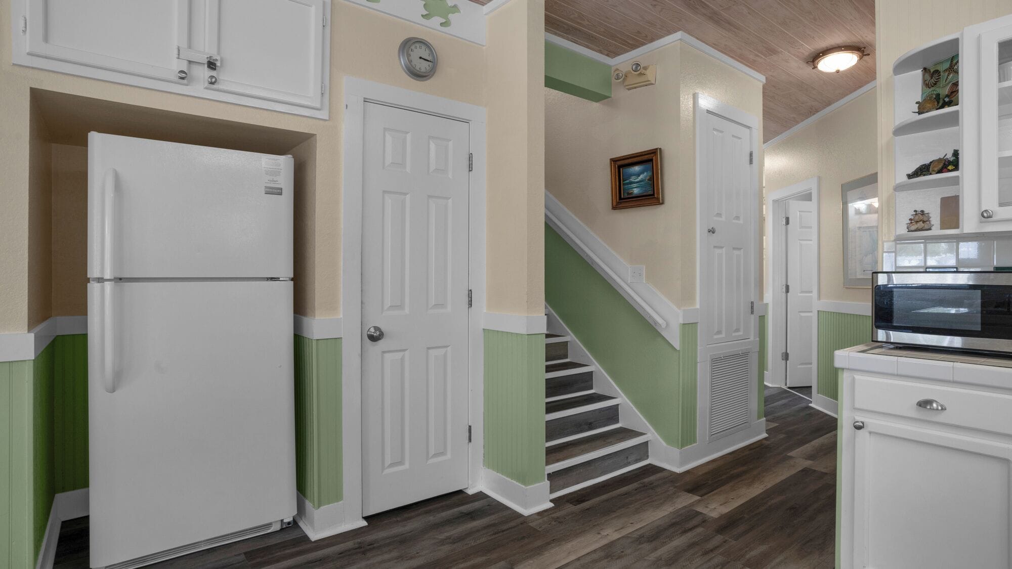A kitchen with white cabinets, a refrigerator, and a microwave.