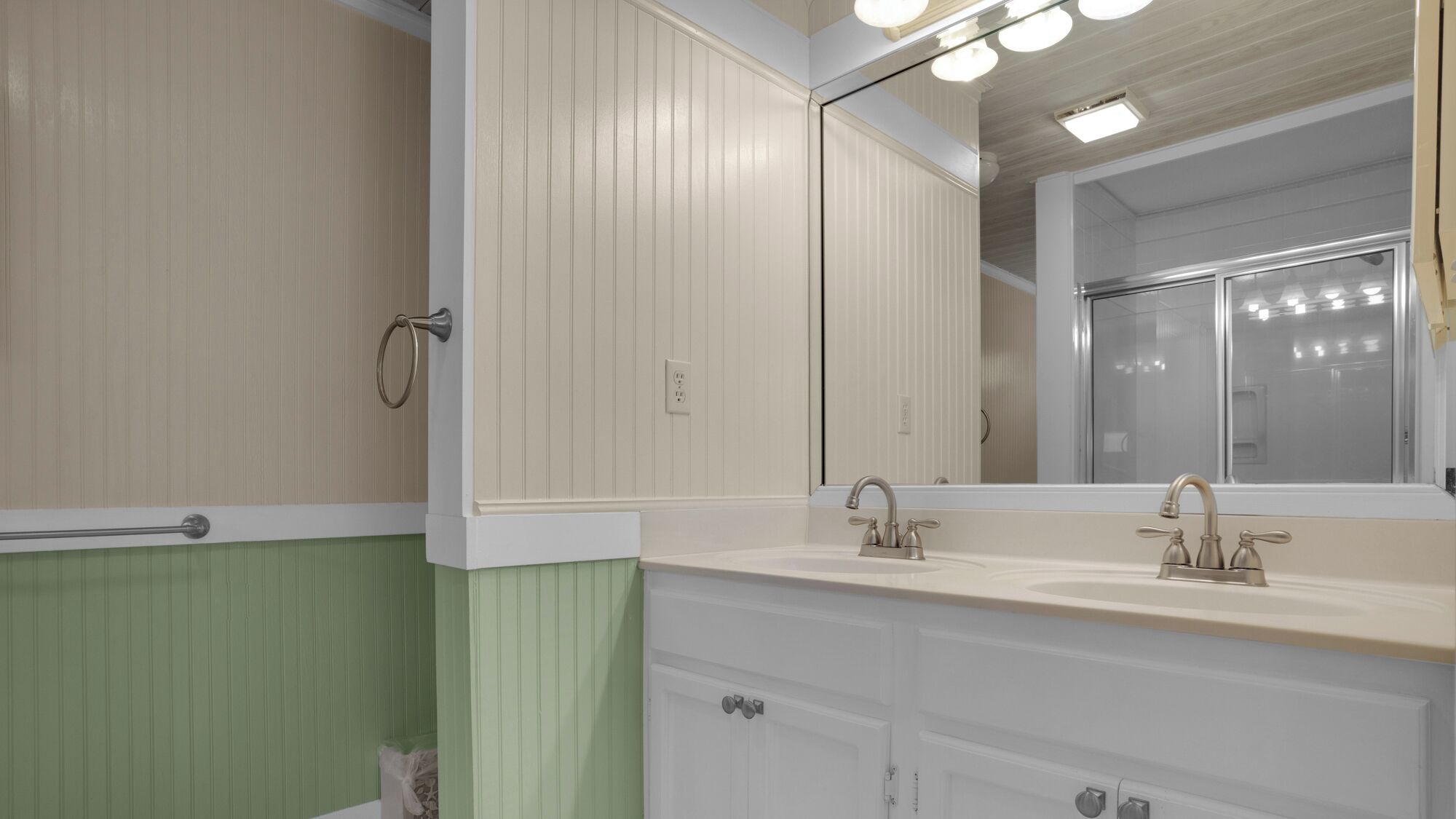 A bathroom with two sinks, a mirror, and a shower.