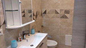 Une salle de bain avec un lavabo blanc, un miroir, des toilettes et des carreaux à motifs.