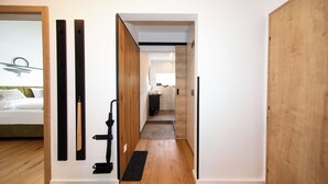 A hallway with wooden flooring, a black vacuum cleaner, and a bed with white bedding in the background. - Ferienwohnung Silvia , Mondsee Zentrum (Mondsee)