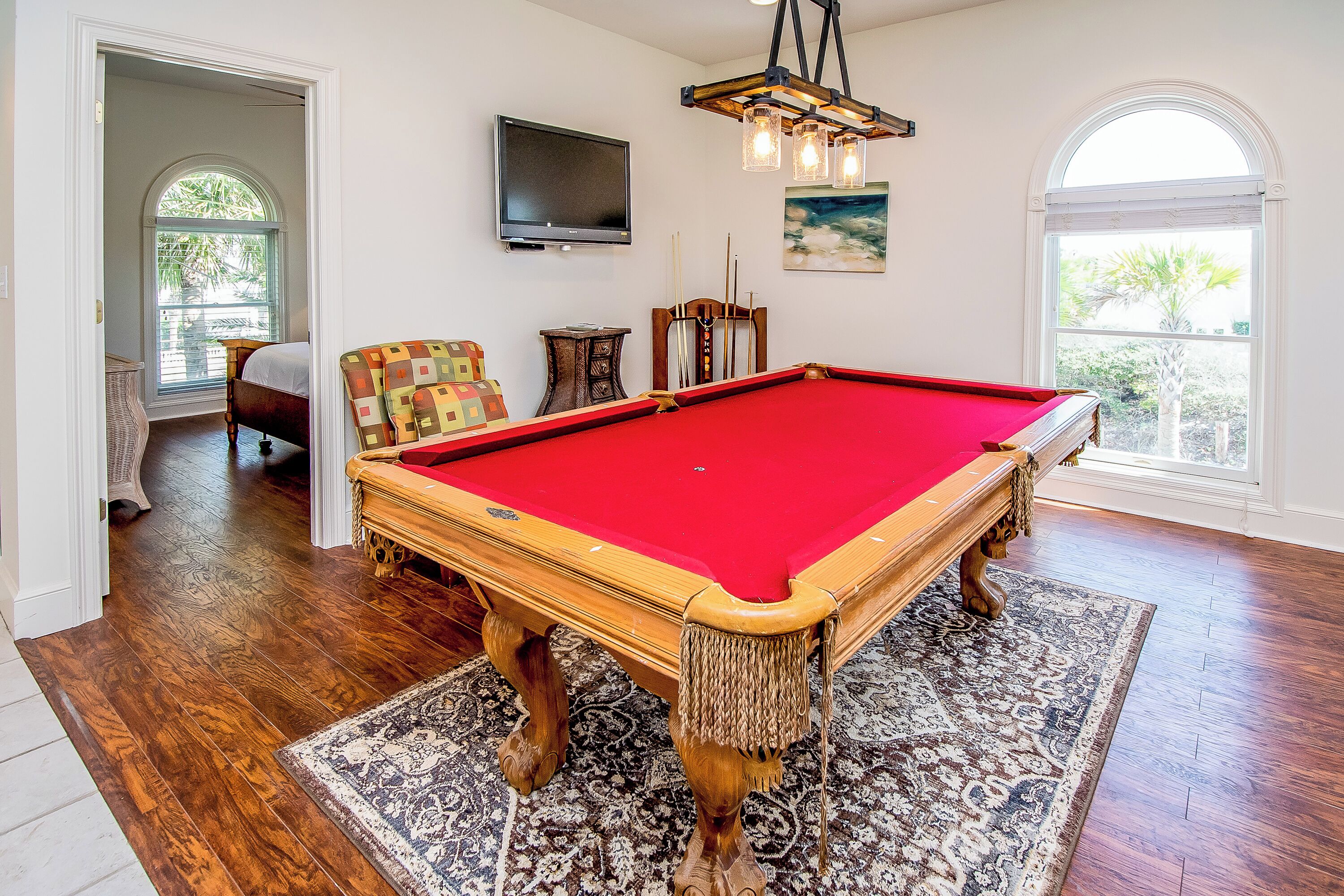 A pool table with a red felt surface, wooden legs, and a decorative fringe.