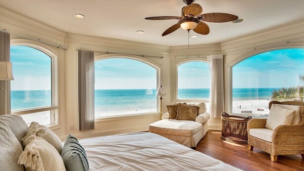 A spacious bedroom with a large bed, a ceiling fan, and a view of the ocean. - Stunning Views! 9BR Gulf Front Home, Pool, Elevator, Pool Table (Destin)