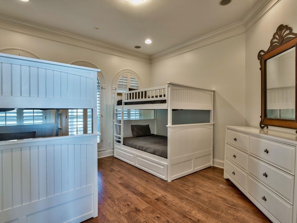 A room with bunk beds, a dresser, and a mirror.