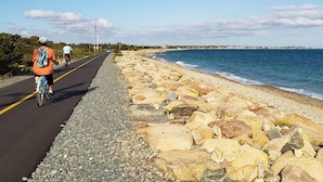 Une route côtière bordée de cyclistes, un littoral rocheux et une vue dégagée sur la mer.