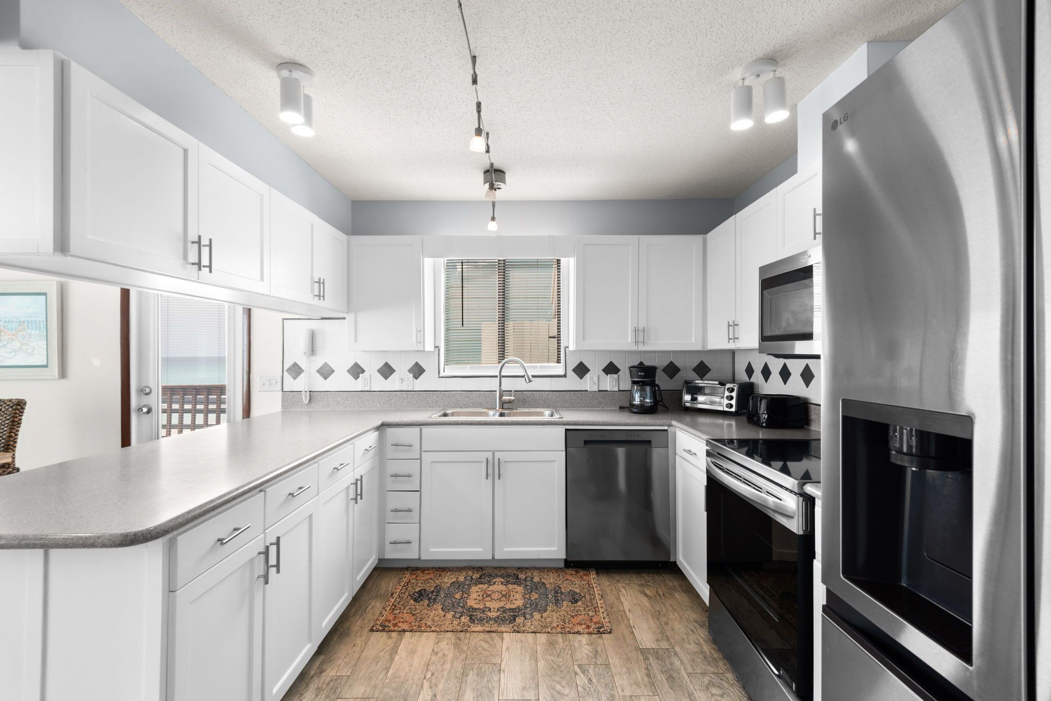 A modern kitchen with white cabinets, stainless steel appliances, a dishwasher, and a microwave.