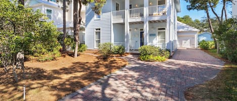A two-story house with a covered front porch, a garage, and a well-maintained garden.