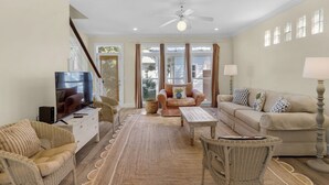 Ein geräumiges Wohnzimmer mit Fernseher, zwei Sofas, einem Couchtisch und Korbstühlen.