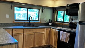A kitchen with wooden cabinets, a stainless steel refrigerator, a microwave, and a coffee maker. - 6 Bed River Home, Right On St. Joseph River. (Union City)
