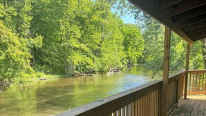 A wooden deck overlooking a river with dense greenery on both sides. - 6 Bed River Home, Right On St. Joseph River. (Union City)