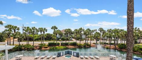 A swimming pool with lounge chairs, a water feature, and palm trees.