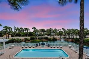A swimming pool with lounge chairs and a view of palm trees and a body of water. - The Salty Dog on 30a: Modern Updates, 1 Minute to the Beach! (Santa Rosa Beach)