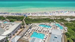 Een resort met diverse zwembaden, toegang tot het strand en verschillende strandparasols.