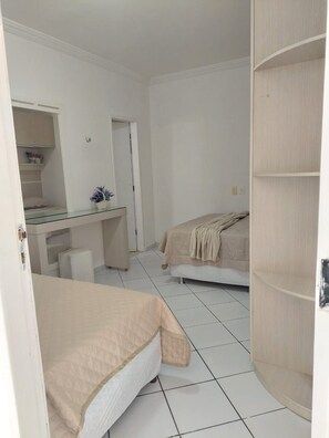 Un dormitorio con dos camas, un escritorio con espejo y un armario.