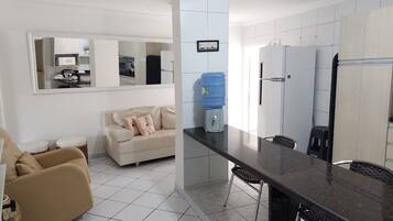 A modern kitchen with a dining area, a water dispenser, and a sofa.
