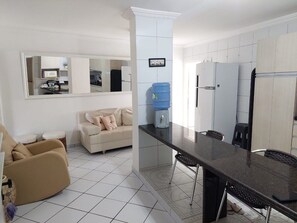 A modern kitchen with a dining area, a water dispenser, and a sofa. - Marinas Tamandaré próximo à Carneiros  (Tamandaré)
