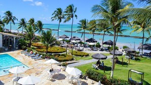 A resort with a swimming pool, lounge chairs, umbrellas, and a view of the beach and ocean. - Marinas Tamandaré próximo à Carneiros  (Tamandaré)