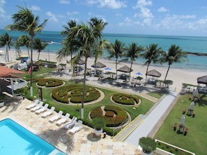 Un resort con piscina, tumbonas, palmeras y vista al mar.