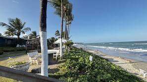 Vista de la playa con palmeras, arena y cielo despejado.