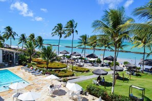A resort with a swimming pool, lounge chairs, umbrellas, and a view of the beach and ocean. - Marinas Tamandaré próximo à Carneiros  (Tamandaré)