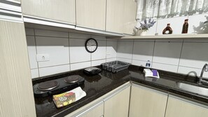 A kitchen with a stove, sink, and a clock on the wall. - Marinas Tamandaré próximo à Carneiros  (Tamandaré)