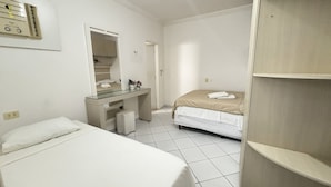 Una habitación pequeña y limpia con cama, escritorio, espejo y armario.