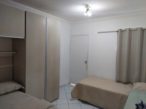 Un dormitorio con dos camas, un armario, una puerta y una cortina.