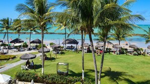 A resort with a beach view, palm trees, and thatched umbrellas. - Marinas Tamandaré próximo à Carneiros  (Tamandaré)