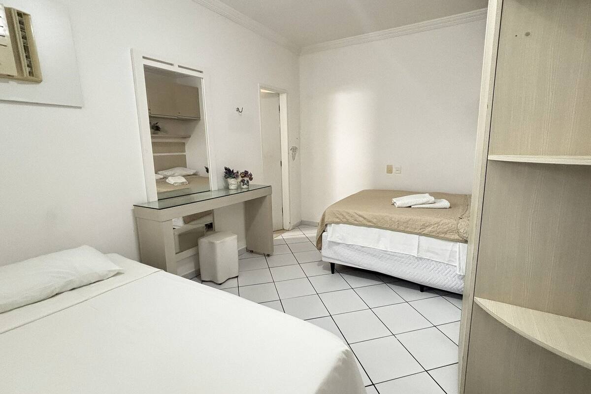 A small, clean room with a bed, a desk, a mirror, and a wardrobe.
