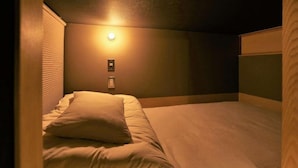 Une chambre d’hôtel avec un lit, une lampe fixée au mur et un panneau de commande.