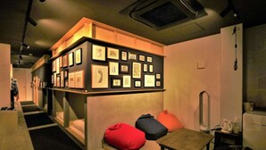 Une pièce chaleureuse avec une exposition d’œuvres d’art accrochée au mur, une petite table et un banc agrémenté de coussins colorés.